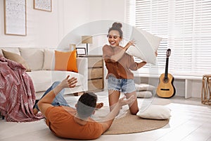 Happy couple having pillow fight in living room