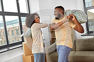 Happy couple having pillow fight at new home