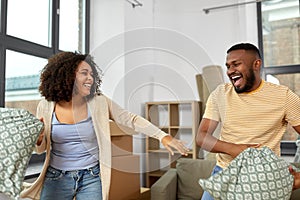 Happy couple having pillow fight at new home