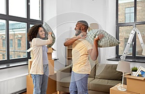 Happy couple having pillow fight at new home