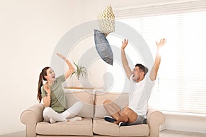 Happy couple having pillow fight in room