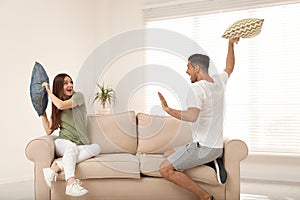 Happy couple having pillow fight in room