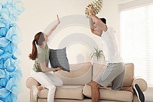 Happy couple having pillow fight in room
