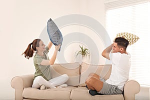 Happy couple having pillow fight in room