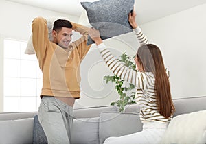 Happy couple having pillow fight in room