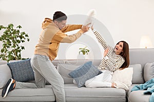 Happy couple having pillow fight in room