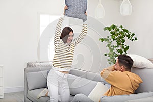 Happy couple having pillow fight in room