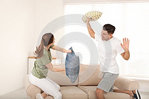 Happy couple having pillow fight in room