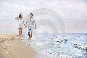 Happy couple having romantic walk on beach. Space for text