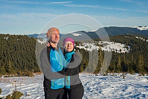 Happy couple hikers hugging and laughing during winter travel in