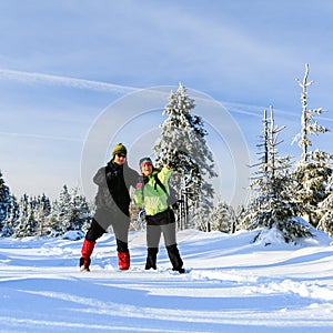 Happy couple hiking on snow trail in winter mountains