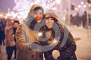 Happy Couple Holding Bengal Lights Standing Outdoor At Night