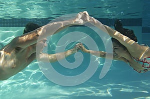 Happy Couple Holding Hands In Swimming Pool Underwater