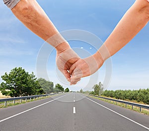 Happy couple holding hands together walking along empty road