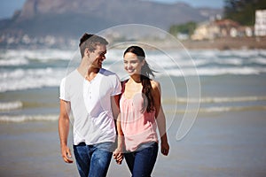 Happy couple, holding hands and walking on beach with love, care or support on outdoor holiday in nature. Young man and