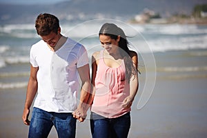 Happy couple, holding hands and walking on beach with support, love or care on outdoor holiday in nature. Young man and