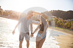 Happy couple holding hands walking at coast laughing