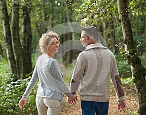 Happy couple holding hands and walking in the forest