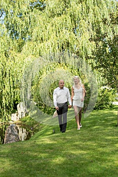 Happy couple holding hands and walking in grass.