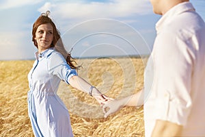 Happy couple holding hands walking through a meadow. The concept of love, good relationships, understanding and harmony