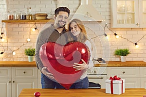 Happy couple holding huge balloon while celebrating Valentine`s Day or having anniversary party