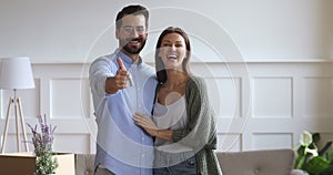 Happy couple holding keys to new home looking at camera