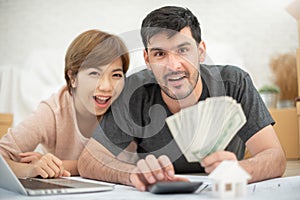 Happy couple holding money and calculating their budget.