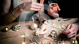 happy couple holding sparkles and champagne glasses New Year party