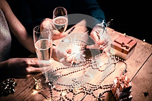 happy couple holding sparkles and champagne glasses New Year party