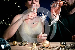 happy couple holding sparkles and champagne glasses New Year party