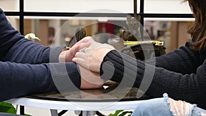 Happy couple holding and touching each others hands at cafe in shopping mall. Male hands are stroking the female hand