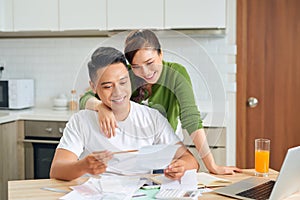 Happy couple at home paying bills with laptop