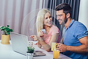 Couple at home paying bills with laptop and credit card