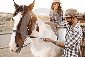 Happy couple with horse having fun at farm ranch - Focus on man face