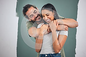 Happy, couple and hug for love, home improvement and smile against a painted wall background. Man and woman smiling for