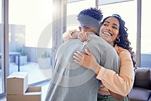 Happy couple, hug and real estate with key for new home, moving in or mortgage loan together indoors. Woman hugging man