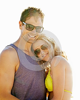 Happy, couple and hug on vacation by beach with sunglasses, smile and holiday for memories or honeymoon. Woman, man and