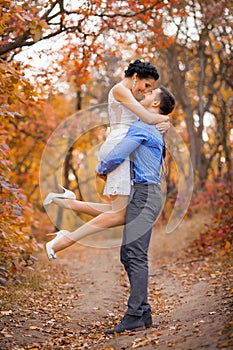 Happy couple hugging in autumn park. Smiling bride and groom in forest, outdoors