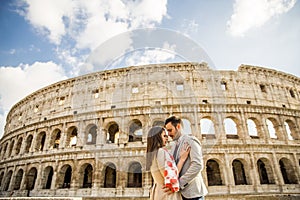 Happy couple hugging in front of Colosseum in Rome, Italy