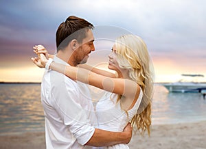 Happy couple hugging over sunset beach background