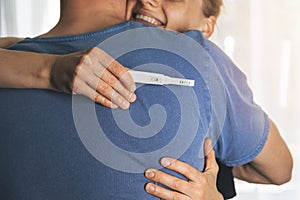 Happy couple hugging after positive pregnancy test