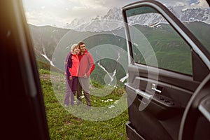 Happy couple hugs on beautiful nature mountains area out of car