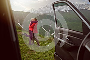 Happy couple hugs on beautiful nature and mountains out of car