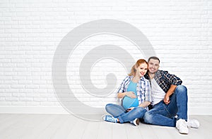 Happy couple husband and pregnant wife near blank brick wall