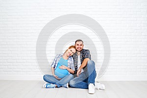 Happy couple husband and pregnant wife near blank brick wall