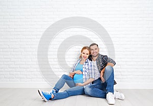 Happy couple husband and pregnant wife near blank brick wall