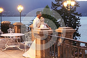 Happy couple husband and wife hugging at balcony in evening near