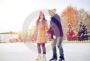 Happy couple ice skating on rink outdoors