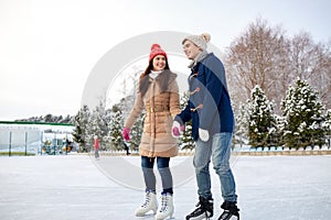 Happy couple ice skating on rink outdoors