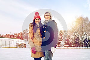 Happy couple ice skating on rink outdoors